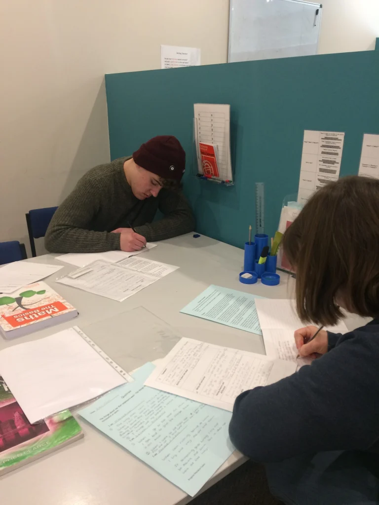 Adult learners working through worksheets with a tutor