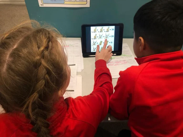 Two children using a tablet maths game about cats