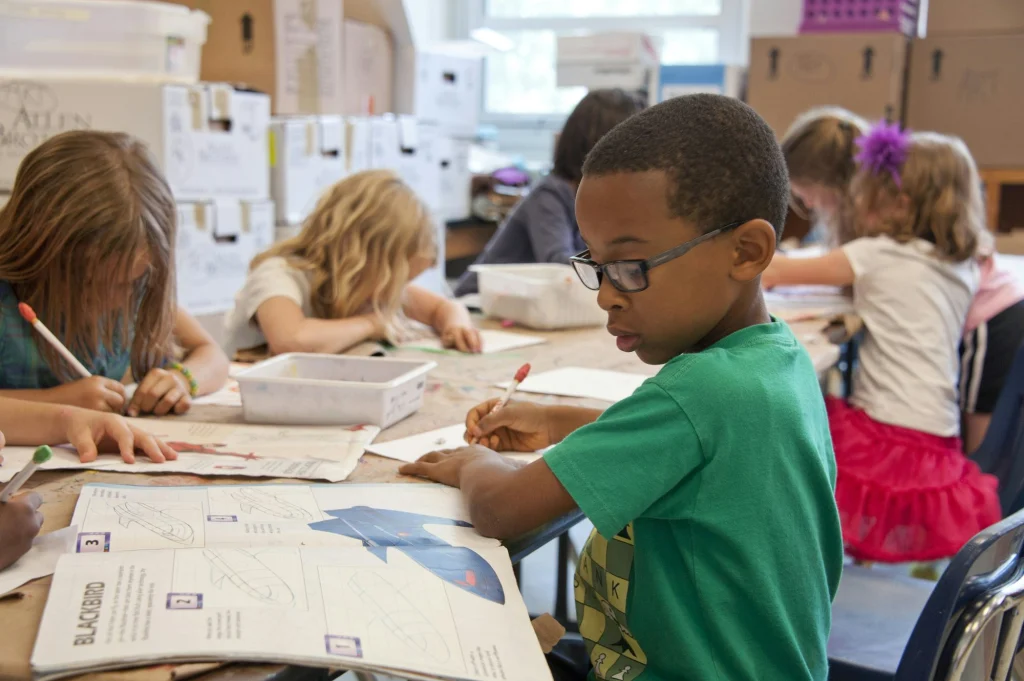 Children drawing and writing at a classroom table