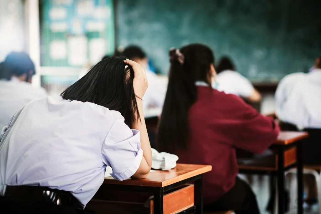 Students sitting an exam at desks in a school hall