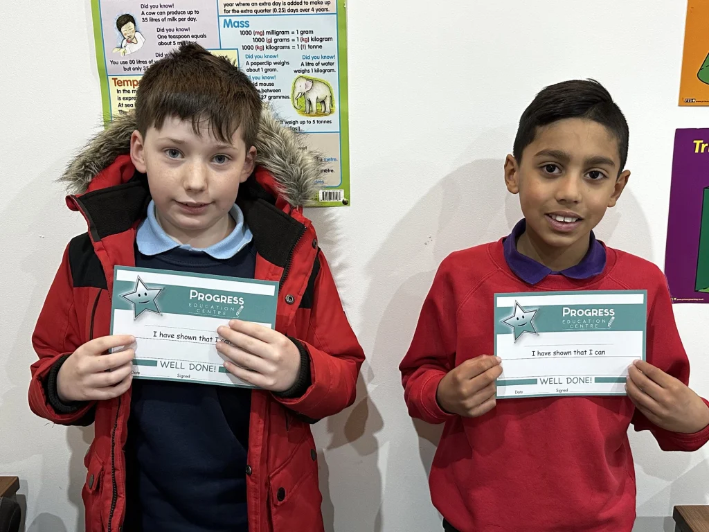 Two boys holding their Progress achievement certificates