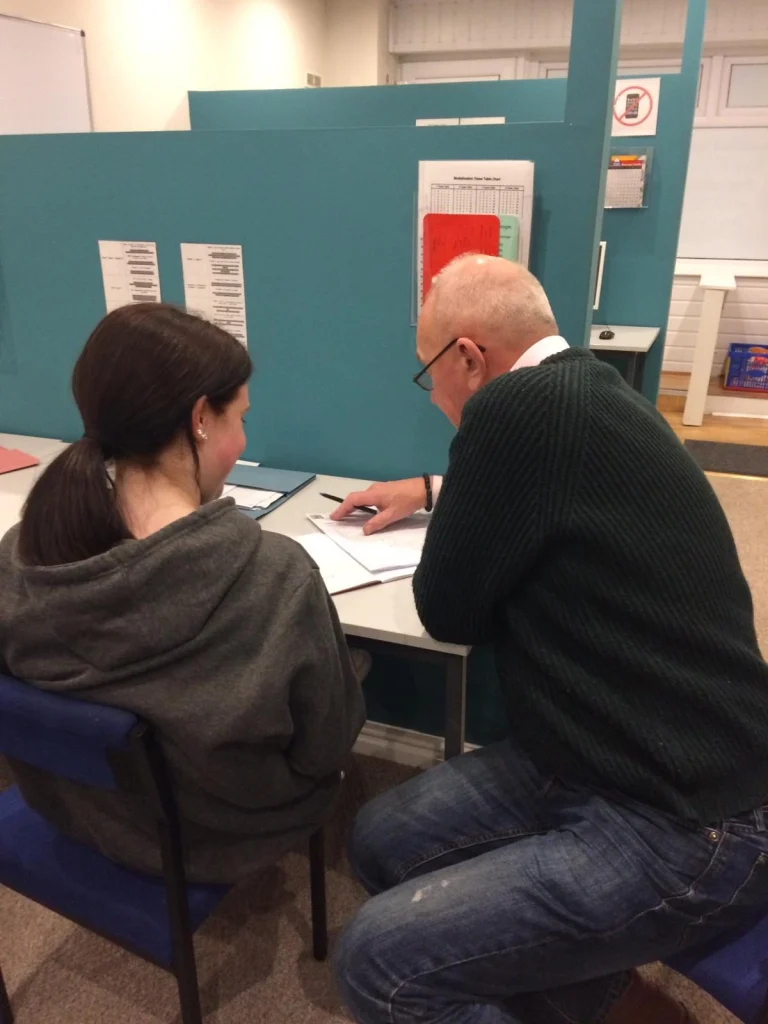 Tutor working one to one with a student at a desk
