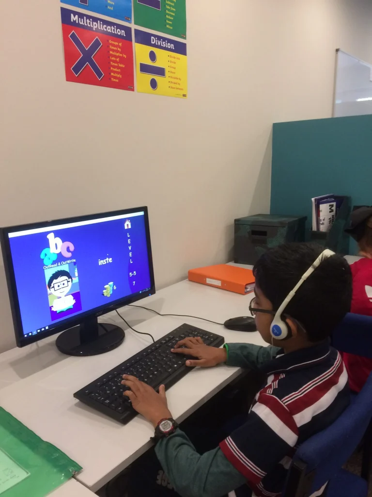 Pupil wearing headphones using a learning program on a computer at the centre