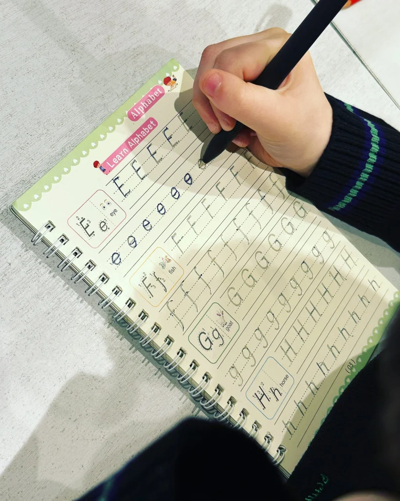 Pupil tracing letters in a handwriting practice copybook
