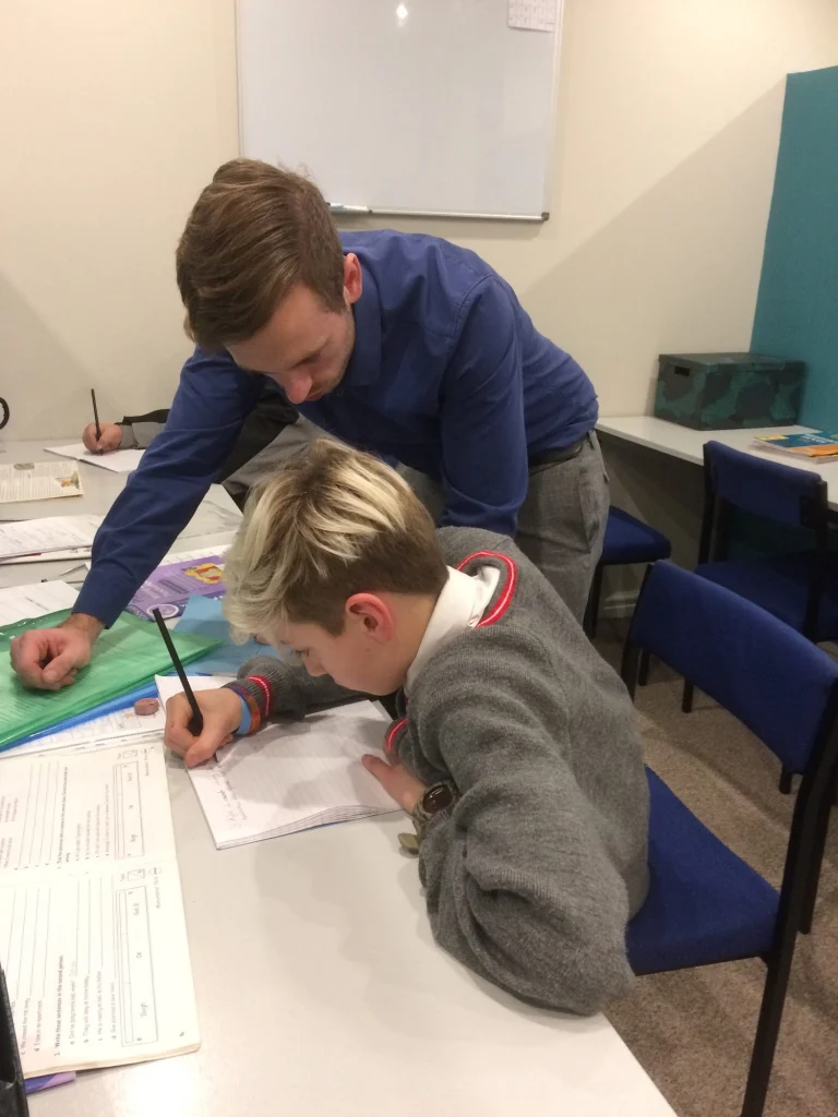 Tutor helping a student with written work at a desk